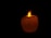 Close-up of a glowing beeswax candle with a soft flickering flame on a minimalist black background.