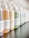 A close-up view of a row of various hair product bottles with pump dispensers arranged neatly. The bottles have white labels with black text, some featuring the brand 'Davines'. The bottles contain different colored liquids, indicating different products such as shampoo and conditioner.