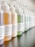 A close-up view of a row of various hair product bottles with pump dispensers arranged neatly. The bottles have white labels with black text, some featuring the brand 'Davines'. The bottles contain different colored liquids, indicating different products such as shampoo and conditioner.
