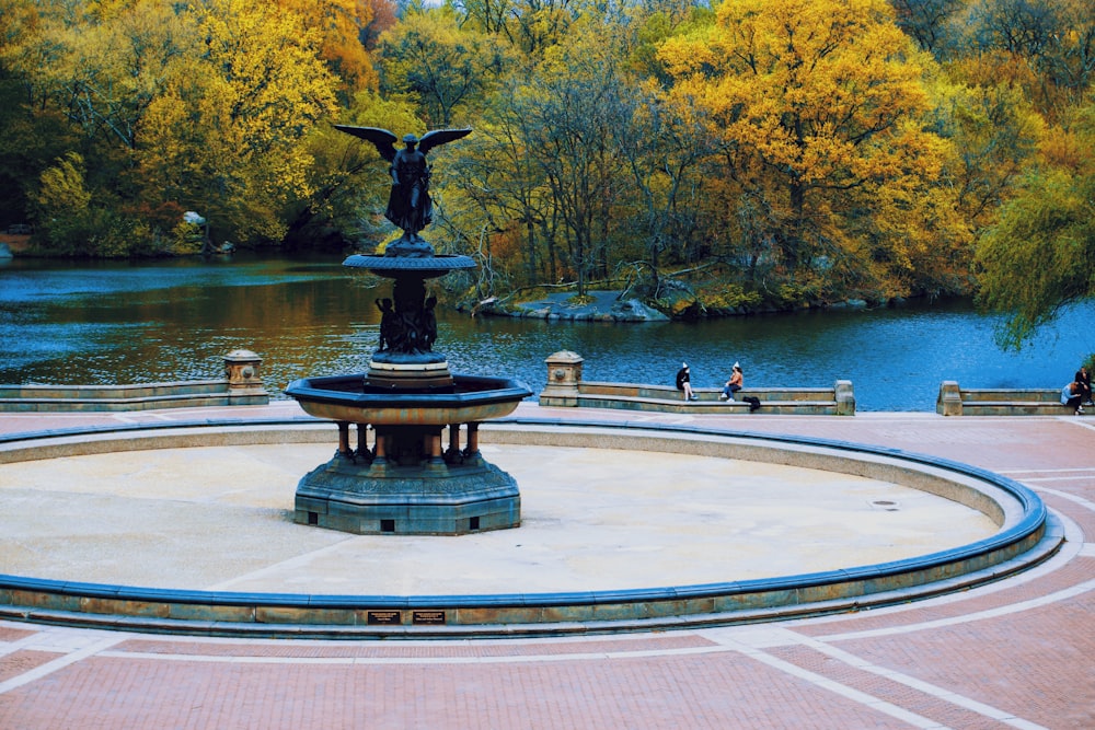 black statue on gray concrete round table near body of water during daytime