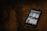 A smartphone displaying a search for a COVID-19 related app is placed on a dark wooden surface. The screen shows various app options with blue and white graphics.