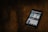 A smartphone displaying a search for a COVID-19 related app is placed on a dark wooden surface. The screen shows various app options with blue and white graphics.