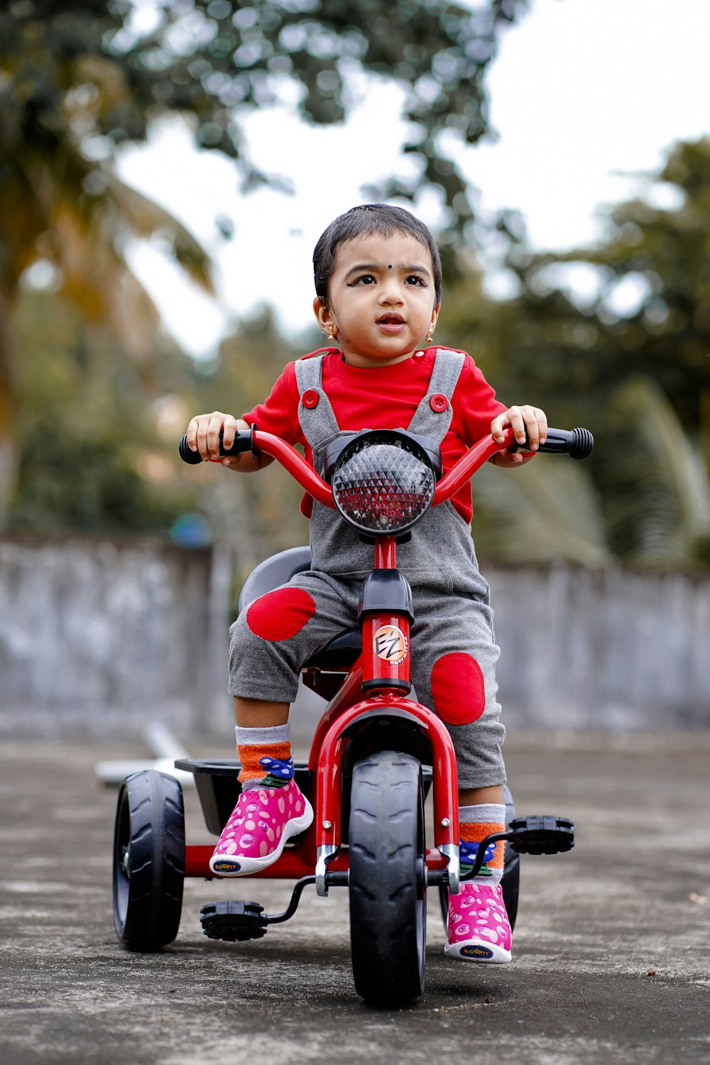 menino na camisa vermelha que monta a bicicleta vermelha durante o dia