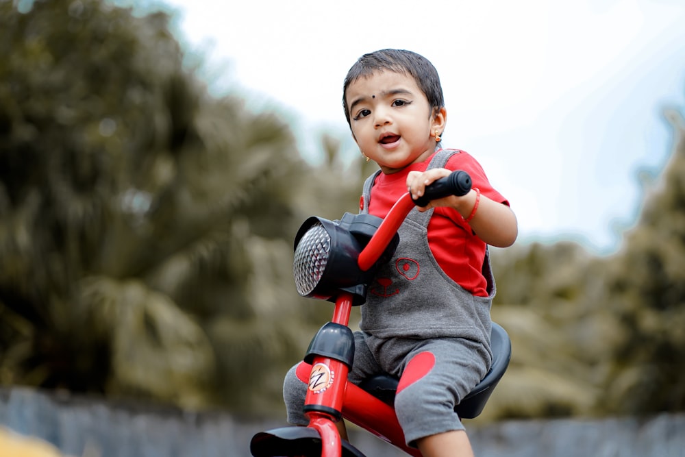 boy in red and blue long sleeve shirt riding on red and black kick scooter during