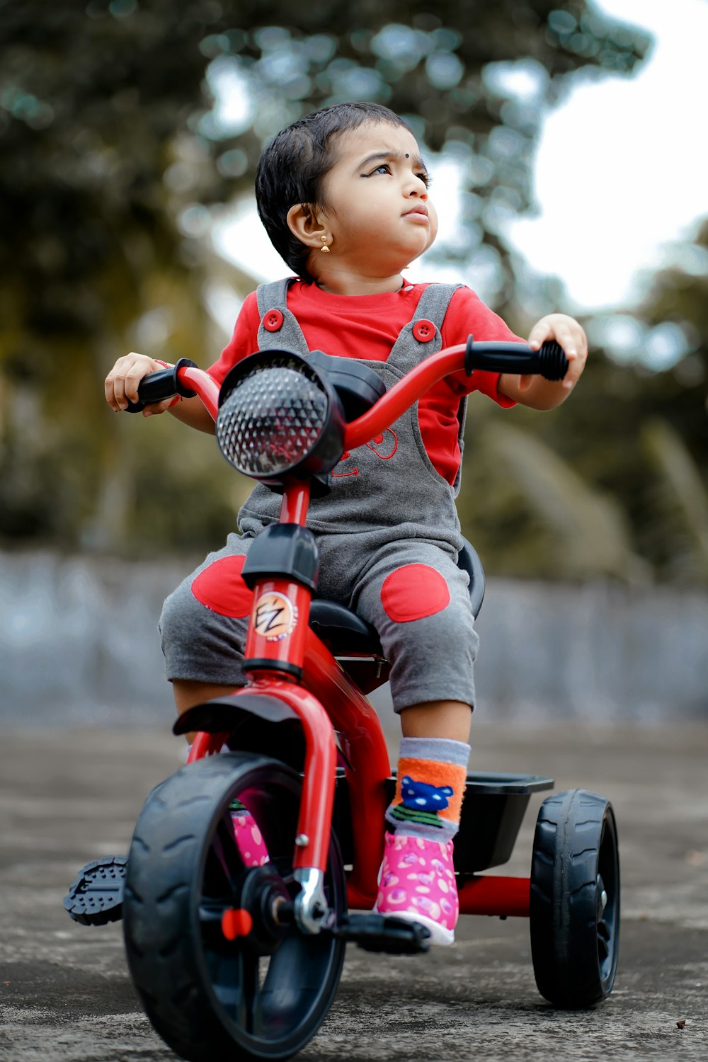criança na camisa vermelha que monta o brinquedo da motocicleta vermelho e preto