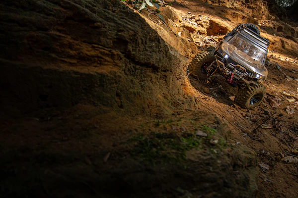 A rugged RC basher tearing through dirt and rocks with dust flying.