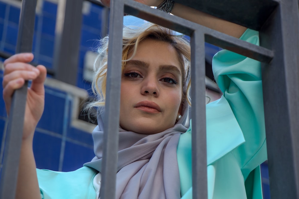 girl in teal hijab near blue metal fence during daytime