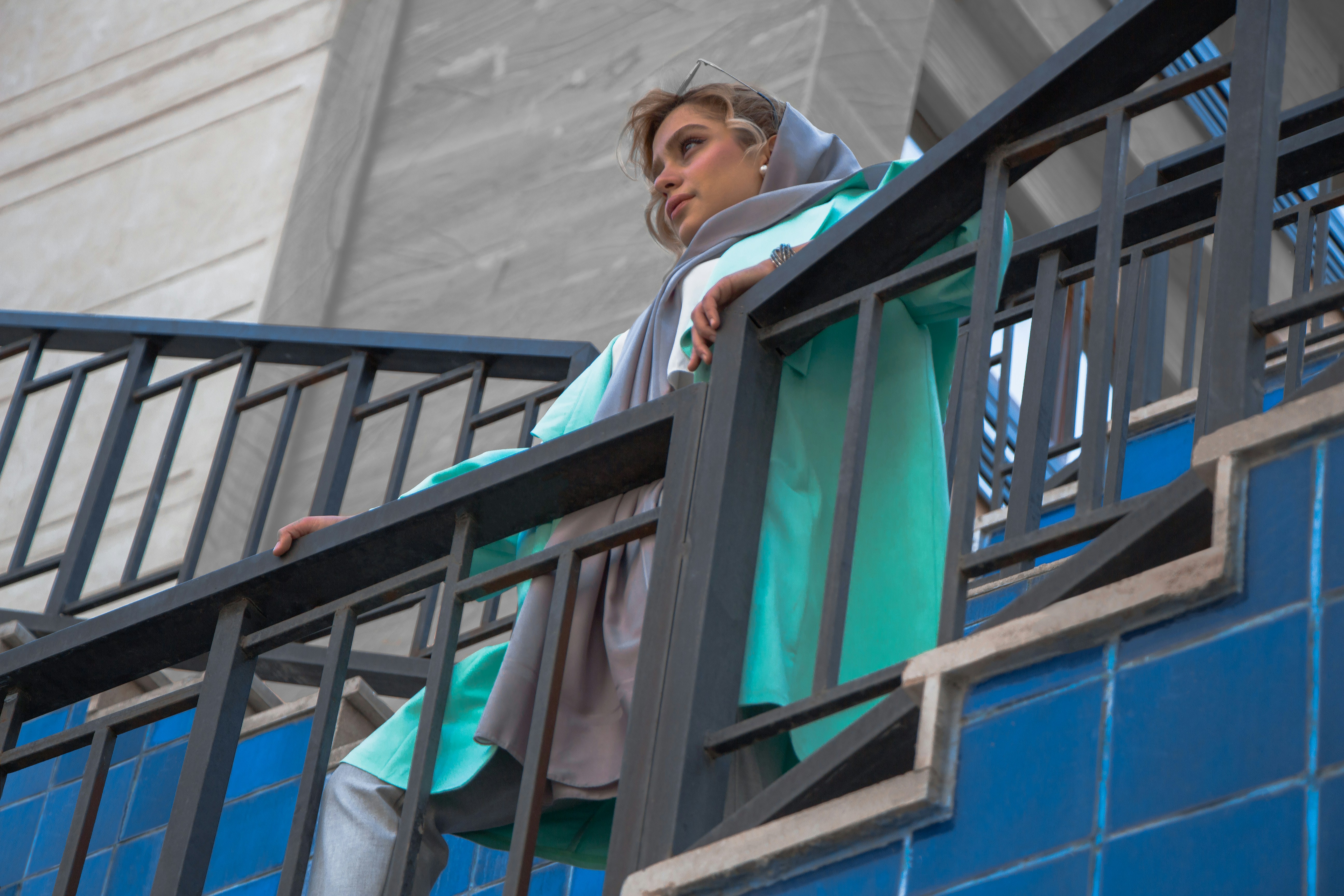 man in white dress shirt and black vest standing beside blue wooden window during daytime