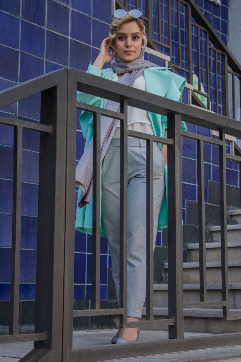 person in gray pants standing beside blue metal railings