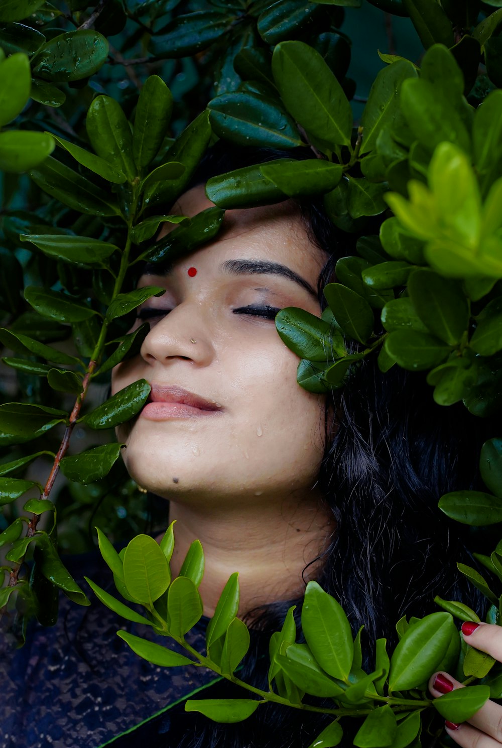 femme en chemise noire à col rond avec des feuilles vertes sur le visage