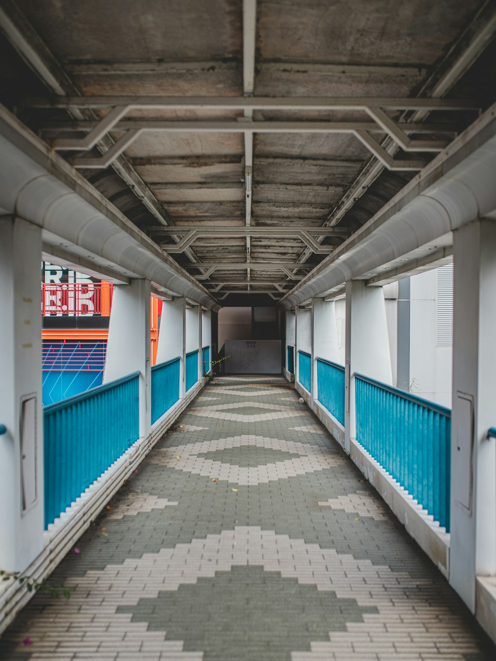 brown brick pathway in between blue and white wall