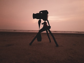 A sleek camera tripod set up on a rocky surface during golden hour.