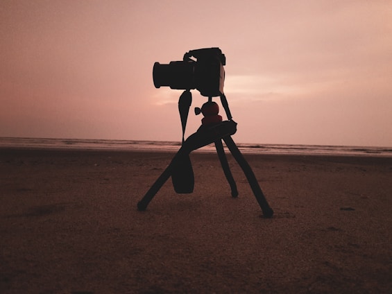 A serene Fijian beach at sunset with a lone camera set up, ready to capture stories.
