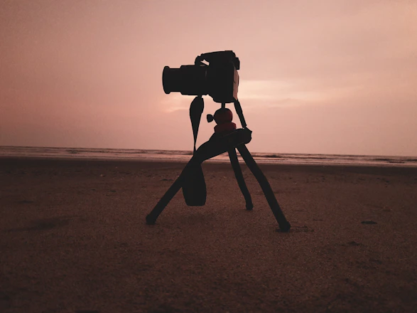 A filmmaker setting up a camera on location during golden hour.