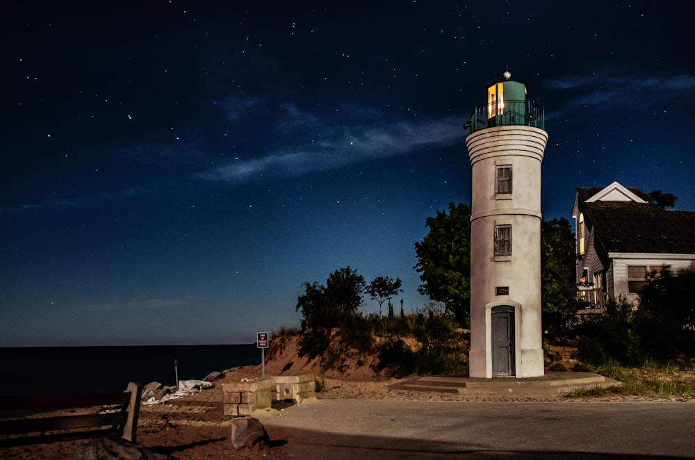 white and black lighthouse near body of water during night time