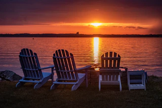 two white wooden armchairs on beach during sunset