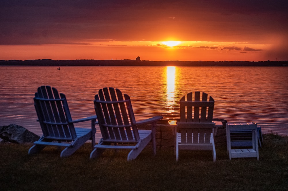 two white wooden armchairs on beach during sunset