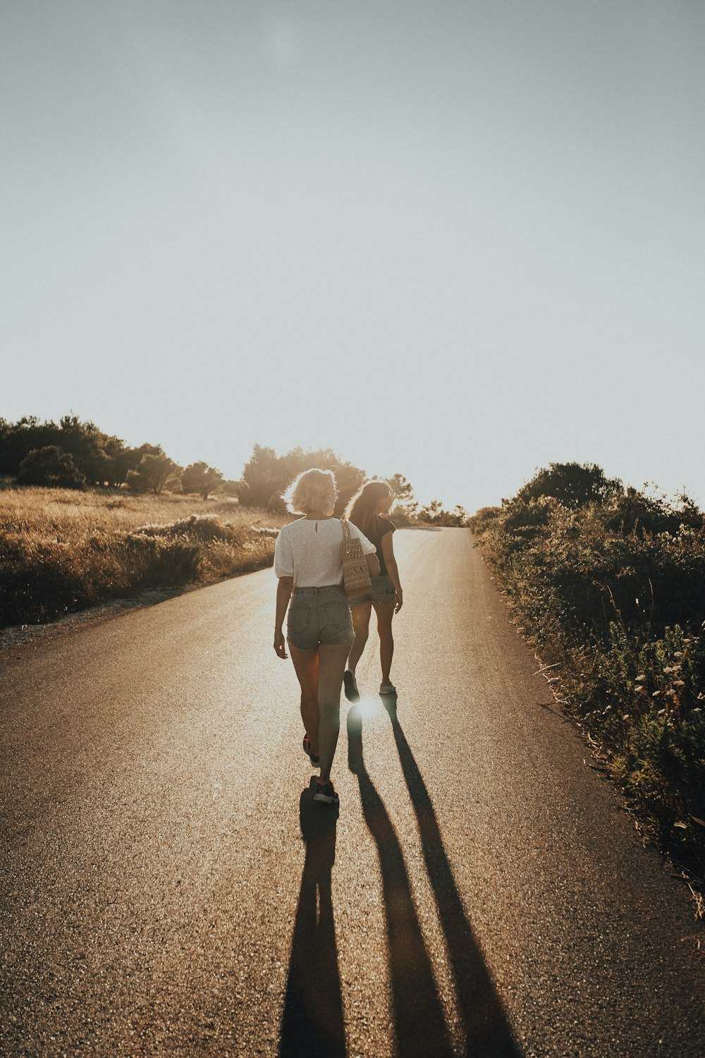 Mujer con camisa blanca y pantalones cortos blancos caminando por la carretera durante el día