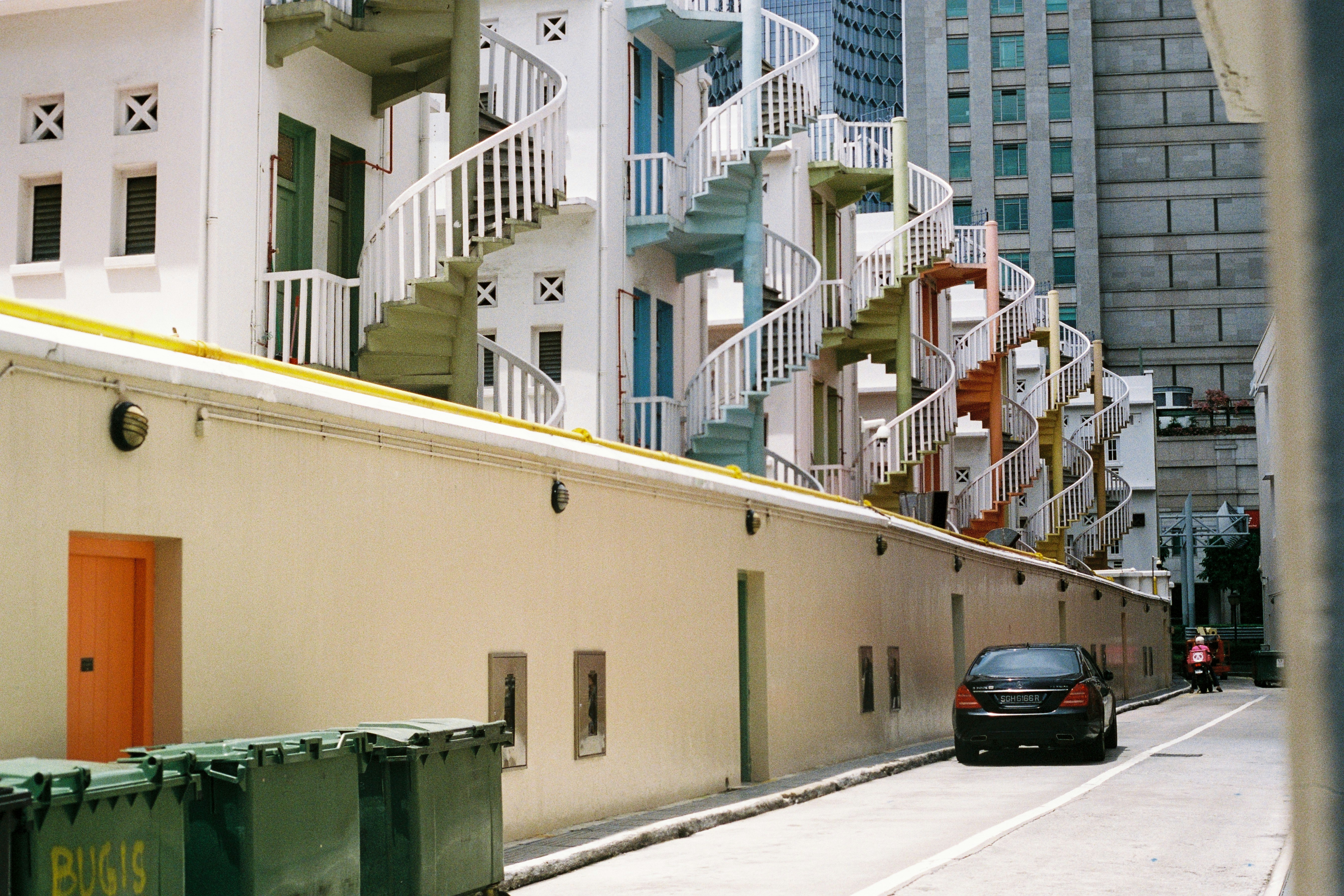 black car parked beside white concrete building during daytime
