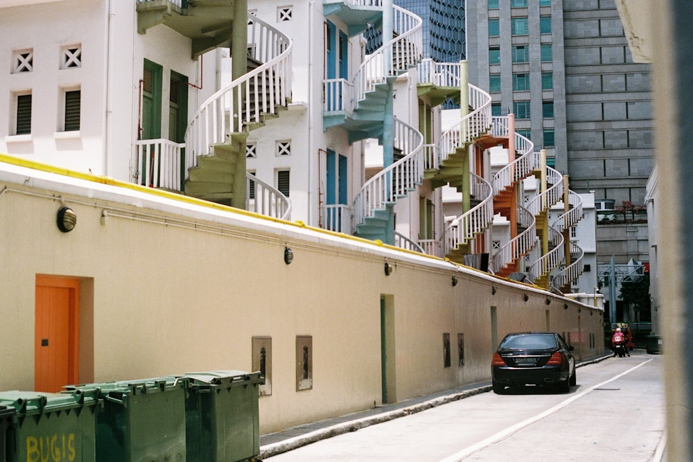 black car parked beside white concrete building during daytime