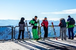 people in green jacket and blue pants standing on ice field during daytime