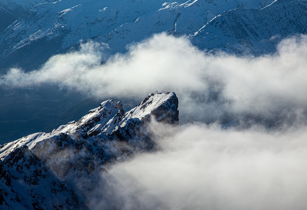 Montaña cubierta de nieve bajo nubes blancas durante el día