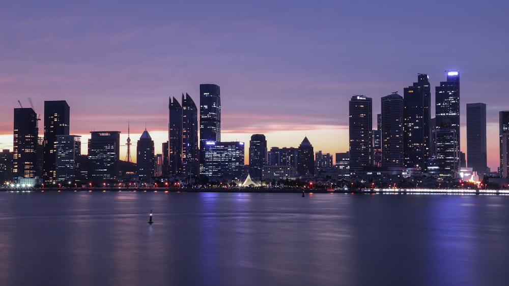 city skyline across body of water during night time