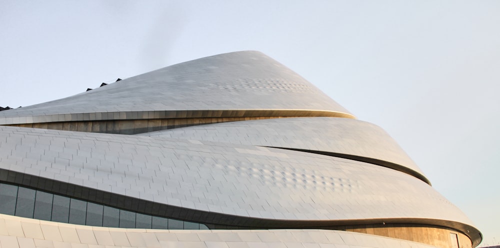 a large building with a curved roof and a sky background