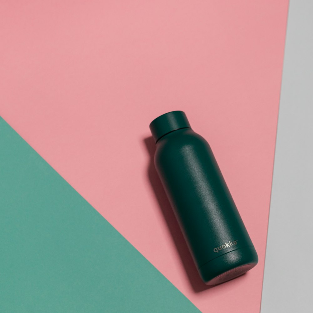 black plastic bottle on pink table