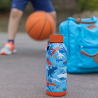 blue and white plastic bottle beside orange basketball on gray concrete floor during daytime