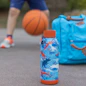 blue and white plastic bottle beside orange basketball on gray concrete floor during daytime