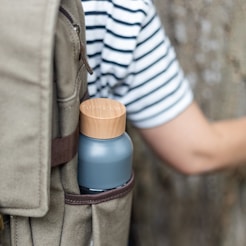 person in white and black striped shirt and brown pants holding blue and white plastic bottle