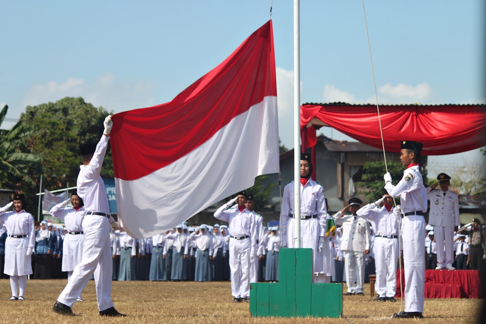 Personas con uniforme blanco sosteniendo banderas durante el día