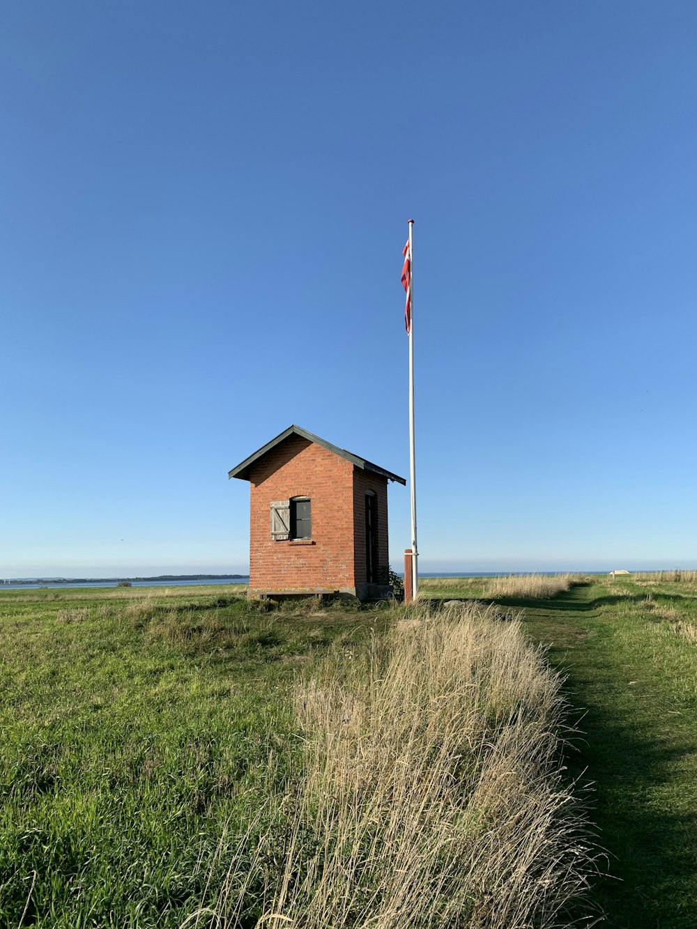 brown and white house near green grass field under blue sky during daytime