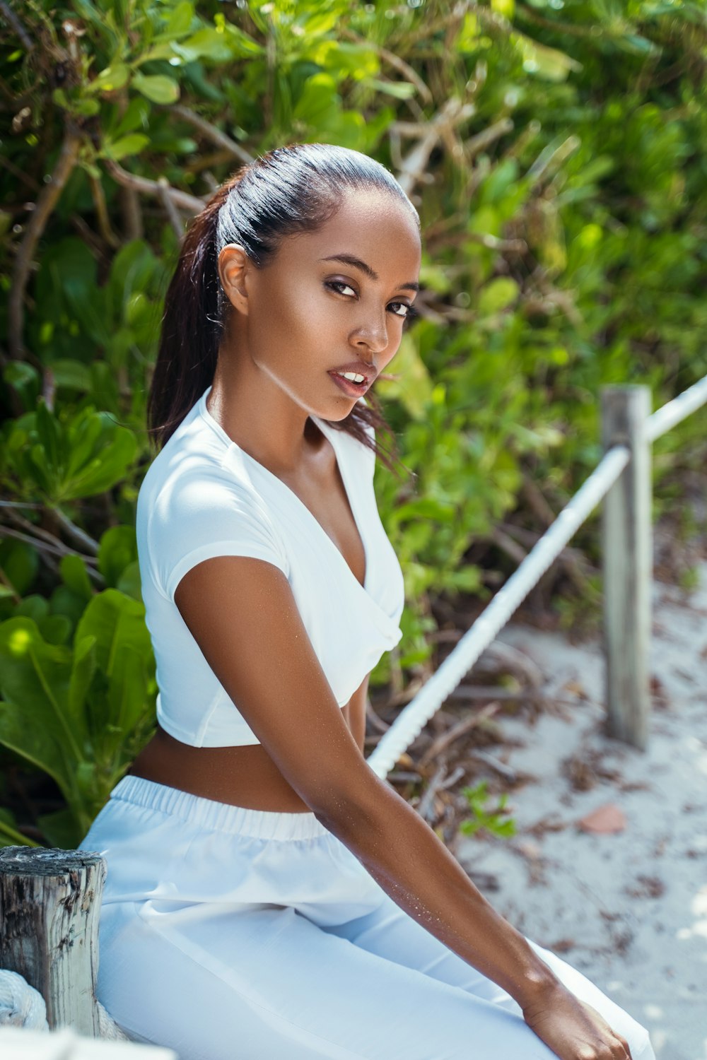 woman in white shirt and white skirt standing near green plants during daytime