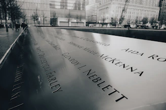 A serene memorial site with a sleek black and white plaque surrounded by soft gray tones.