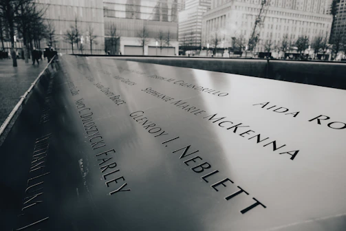 A serene memorial site with a sleek black and white plaque surrounded by soft gray tones.