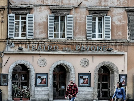 Woman in red and white dress standing in front of brown concrete building during daytime — Perugia, Italy