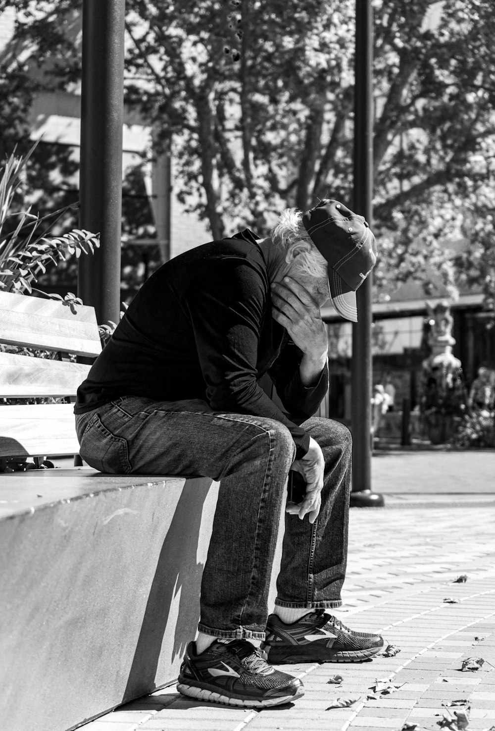 Hombre con chaqueta negra y pantalones sentado en el banco