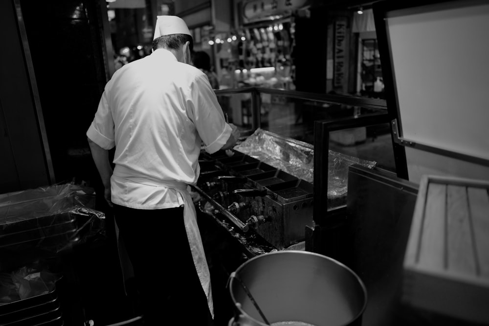 man in white dress shirt and black pants standing in front of counter