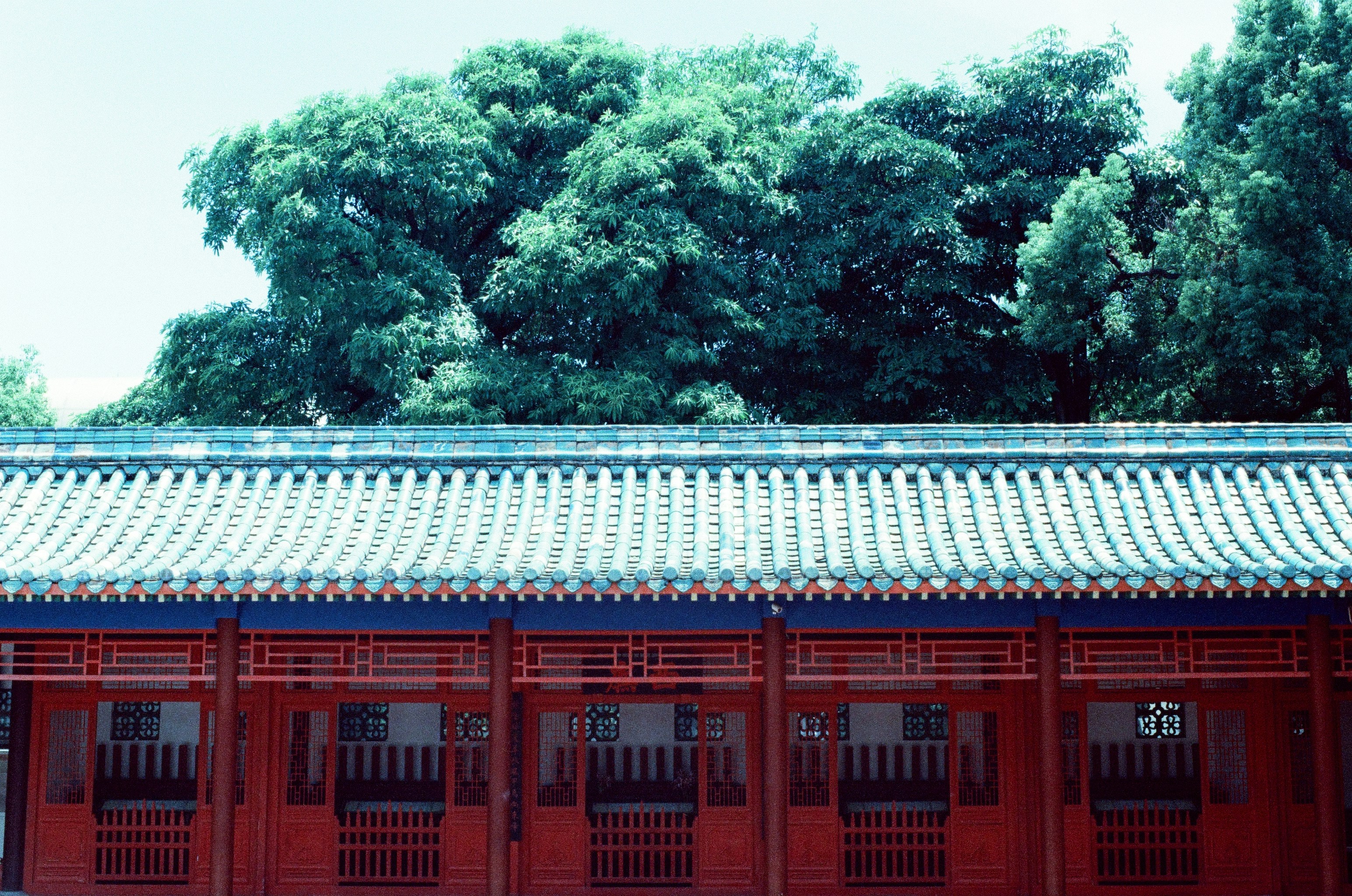 red and white concrete building near green trees during daytime, 