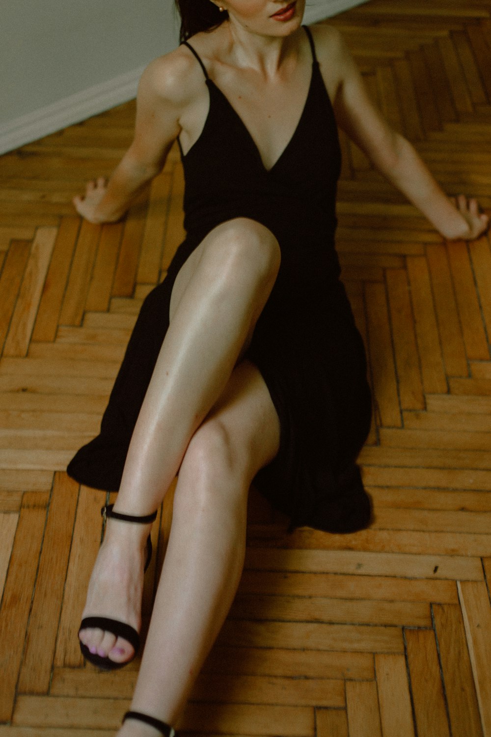 woman in black tank top sitting on brown wooden floor