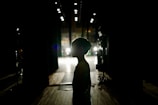 silhouette of man walking on sidewalk during night time