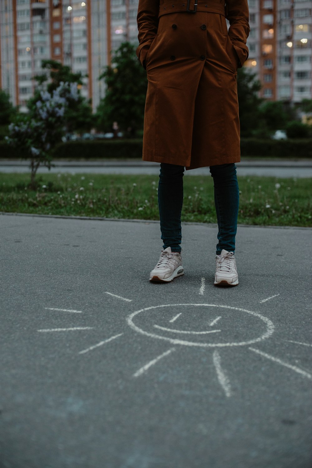 Personne en manteau brun et pantalon noir debout sur une route en béton gris pendant la journée