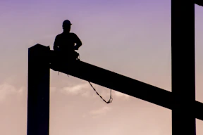 silhouette of man sitting on electric post during daytime
