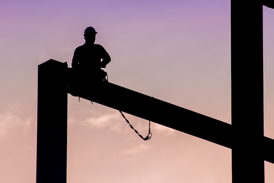 silhouette of man sitting on electric post during daytime