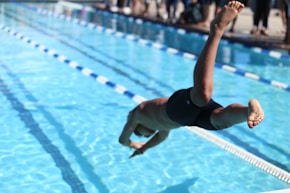 woman in black one piece swimsuit jumping on swimming pool during daytime