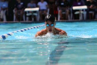boy in swimming goggles in swimming pool during daytime