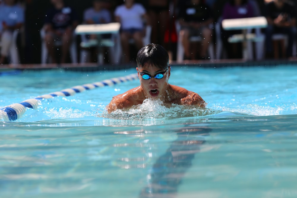 boy in swimming goggles in swimming pool during daytime