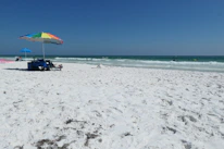 Friendly team member helping a customer choose a beach umbrella on a sunny Oak Island day.